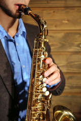 Fototapeta na wymiar The musician with sax on wooden background, close up