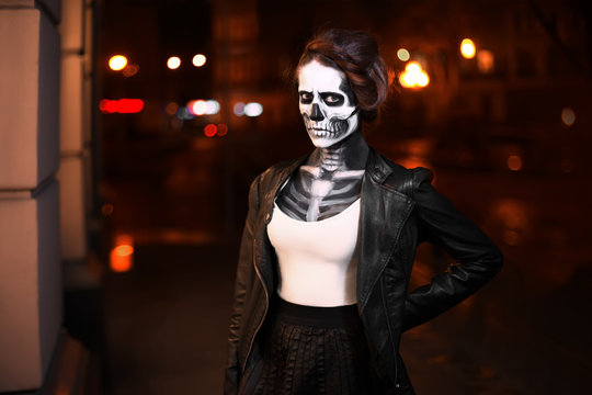 Young woman walking on city avenue. Face art for Halloween party. Street portrait