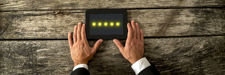 Top view of male hand holding digital tablet with five golden st