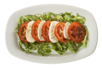 Italian salad - Caprese salad, tomato and mozzarella with spices, served on a white plate. Isolated on white.