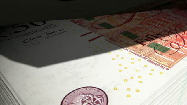 An extreme closeup of british pound stirling banknotes flipping through in a counting machine