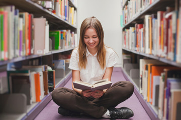 girl reading in the library, smiling happy student