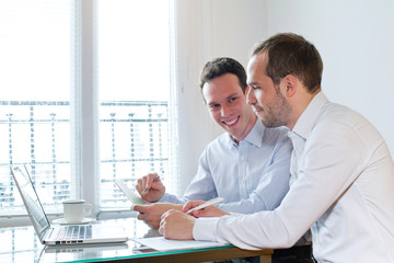 two smiling happy business men working on project in the office