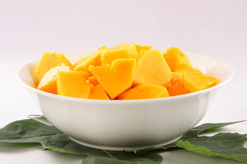 Bowl  of  papaya fruit slices with papaya leaves,.