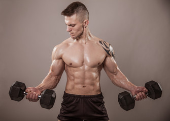 Fototapeta na wymiar Muscular man exercise with dumbbells.