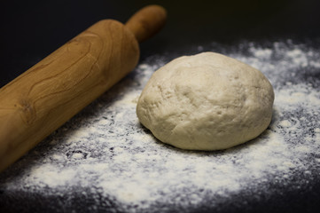 homemade pizza dough with rolling pin on the wooden table