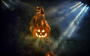 A ghostly ghoul surrounded by fog is guarding a smiling Halloween pumpkin