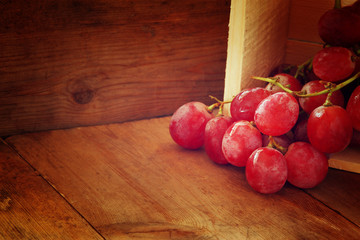 low key image of red grapes over wooden textured table
