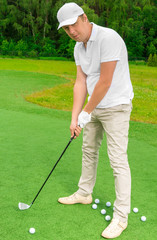 male 30 years on a golf course with a golf club and balls