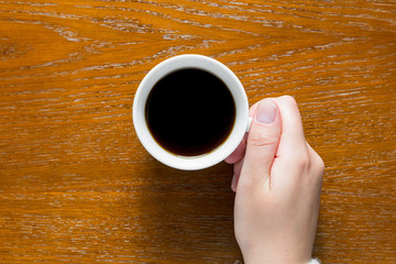 Hand holding coffee on the table top view