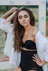 Beautiful young brunette woman in black lingerie and white shirt