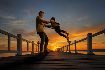 Father plays with his girl on the beach at sunset