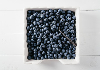 Blueberries in ceramic plate on white wood background