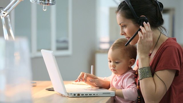 Busy businesswoman working with baby on lap