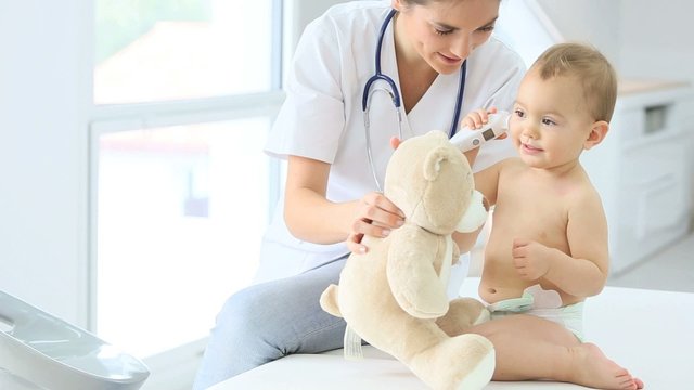 Baby in doctor's office playing with teddy bear
