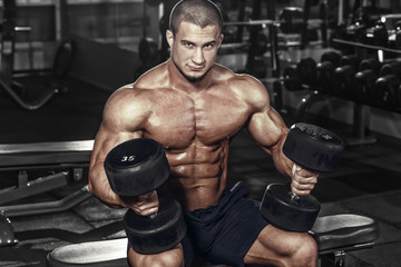 Fototapeta na wymiar Athlete muscular bodybuilder man demonstrates his muscles in the gym