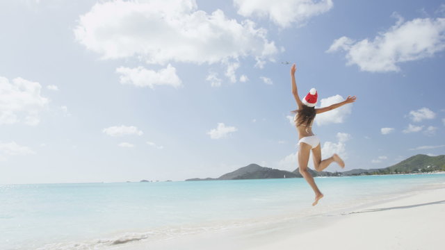 Christmas holiday travel woman jumping on beach