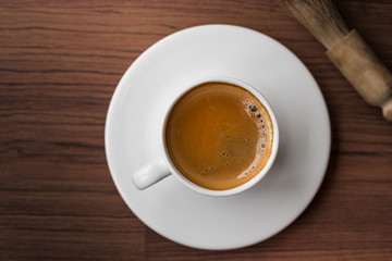 cup of fresh espresso with cleaning blush of coffee machine on table, view from above