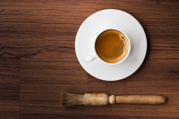 cup of fresh espresso with cleaning blush of coffee machine on table, view from above