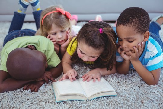 Happy multi-ethnic kids reading a book together