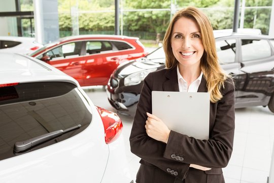 Smiling saleswoman holding document while looking at camera