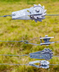 Ratchet fence tensioners for tightening wire fences with blurred