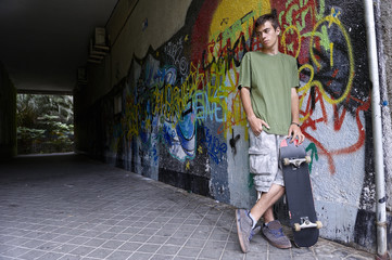 Obraz na płótnie Canvas Young skater leaning against a wall with graffiti