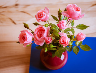 Pink roses in a vase on wooden background