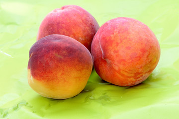 Red peaches on a green background, close up