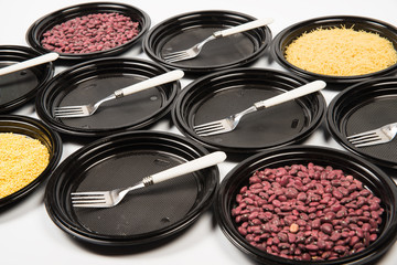 Composition from black plastic plates with forks, haricot and no