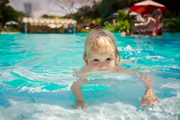 Fototapeta na wymiar small girl walks on hands in shallow transparent pool water