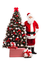 Santa Claus standing next to a Christmas tree