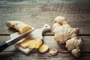 Ginger root on cutting board on rustic wooden kitchen table.