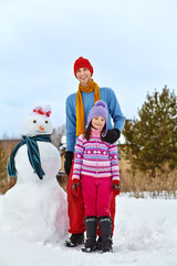Fototapeta na wymiar Father and daughter with snowman