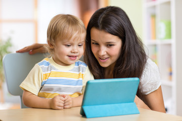Mother and son kid playing with tablet computer indoors