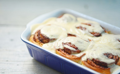 Fresh cinnamom rolls in ceramic baking dish on white table