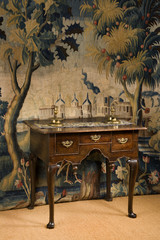 old antique European lowboy dresser against period tapestry
