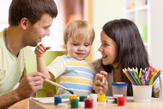 kid painting together with parents ay home