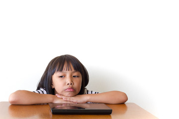 Little girl with bored tablet pc sitting on the wooden table - Technology and children concept