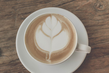 Close up a cup of coffee latte art on old wooden background - Vintage filter effect