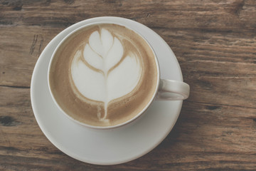 Close up a cup of coffee latte art on old wooden background - Vintage filter effect