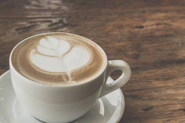 Close up a cup of coffee latte art on old wooden background - Vintage filter effect