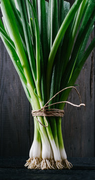Green onions on a black wooden background
