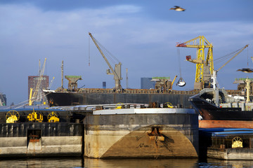 Fototapeta na wymiar Push barges moored in the port of Rotterdam and a bulk carrier is getting loaded in the background