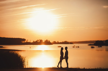 Fototapeta premium Romantic couple standing at sunset. copy space
