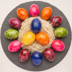 Osterdekoration mit Ostereier im Nest auf Schieferplatte