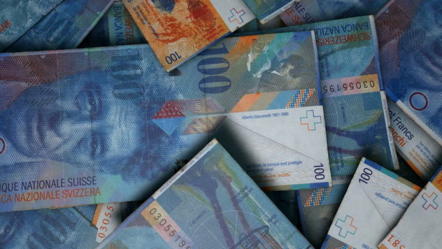 An extreme close up pan of a pile of randomly scattered swiss franc banknotes