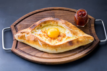 Ajarian khachapuri on dark table with raw egg close up