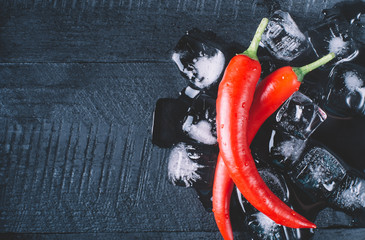 Red pepper and ice on a black wood background top view horizontal - Powered by Adobe