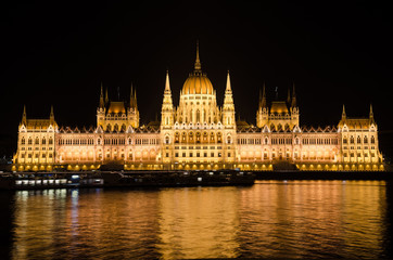 Fototapeta na wymiar Night view of the famous Parliament building of Hungary in Budapest, illuminated by electric light. The reflections of electric lighting in the waters of the Danube River. 